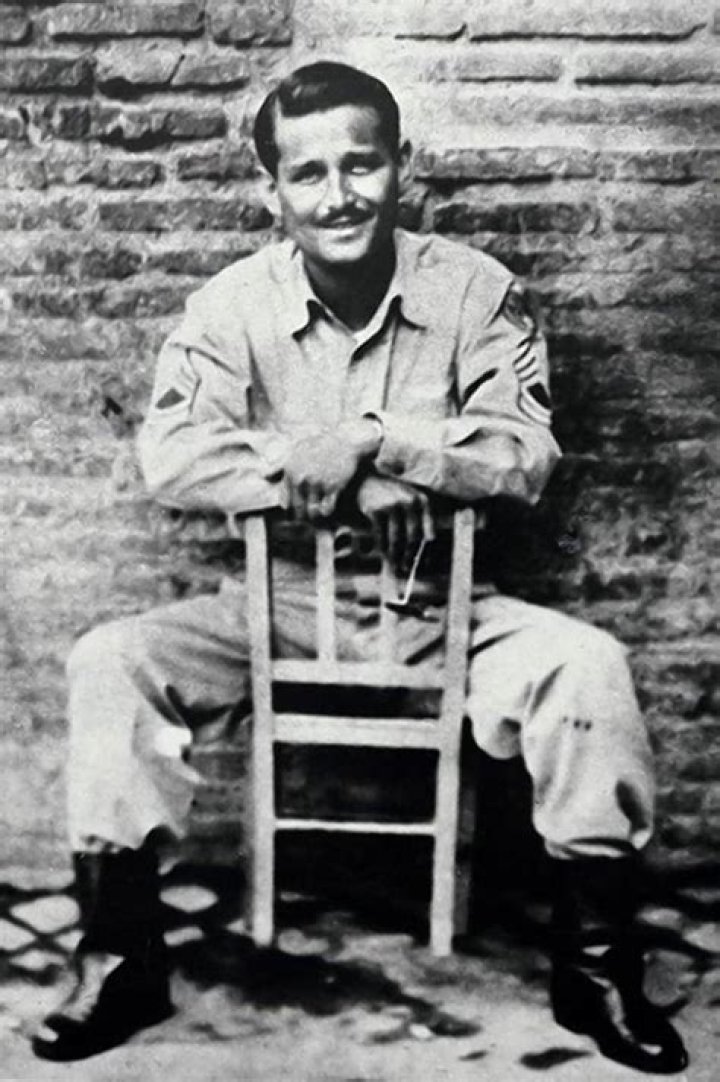 Norman Lear is shown sitting at his desk in a black and white photo. 